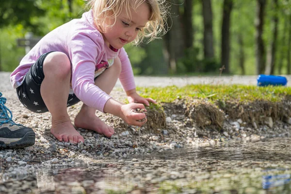 Junges Mädchen spielt mit Steinen im See. — Stockfoto