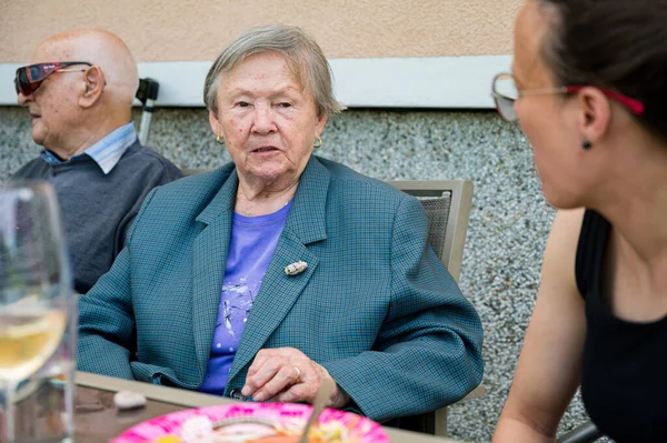 Oudere dame praat aan tafel met jongere vrouw. — Stockfoto