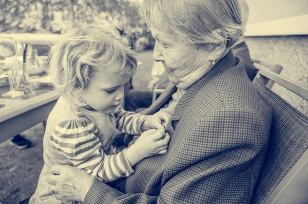 Grandmother having her grandaughter in lap and talking.