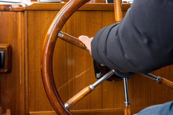Kapitan trzyma drewniane koło kierownicy wykonane z mahoniu. — Zdjęcie stockowe