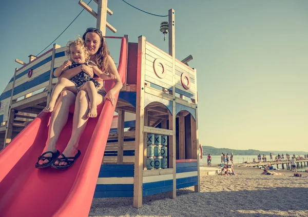 Mãe e filha montando um slide na praia . — Fotografia de Stock