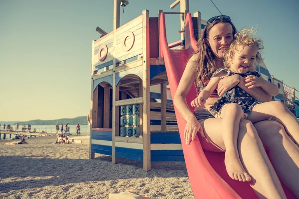 Mãe e filha montando um slide na praia . — Fotografia de Stock