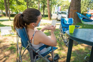 Sağlık maskesi takan kadın kamp merkezinde Covid-19 durumunu kontrol ediyor..