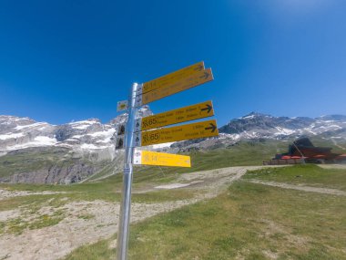 Cervinia, İtalya - 12 Temmuz 2020: Cervinia üzerinde farklı dağ rotalarında rehberlik eden yürüyüşçülerin bulunduğu sarı tabela direği