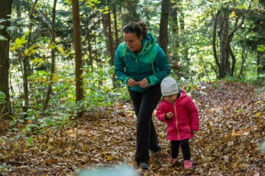 Anne ve kızı birlikte sonbahar ormanlarını keşfediyorlar..
