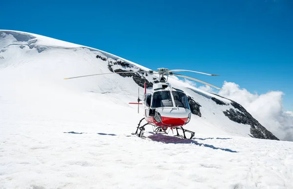 冬天，白色和红色的直升机在雪地上着陆. — 图库照片