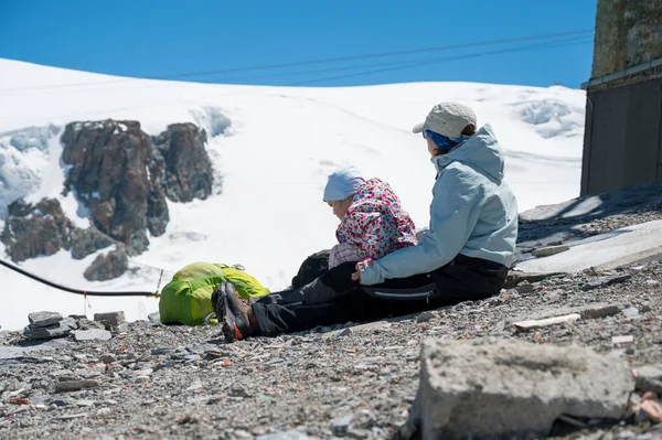 Anne ve kızı yerde oturmuş kayak merkezinin manzarasının keyfini çıkarıyorlar.. — Stok fotoğraf