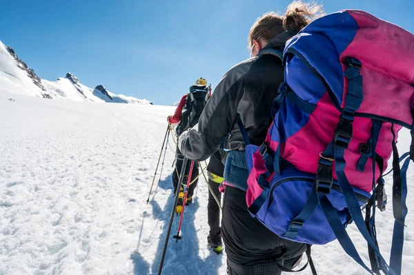 Touw teamlid standpunt met bergbeklimmers wandelen op sneeuw en ijs bij zonnig weer. — Stockfoto