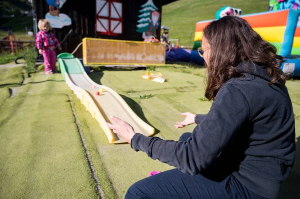 Mãe brincando com sua filha bonito no parque infantil ao ar livre. — Fotografia de Stock