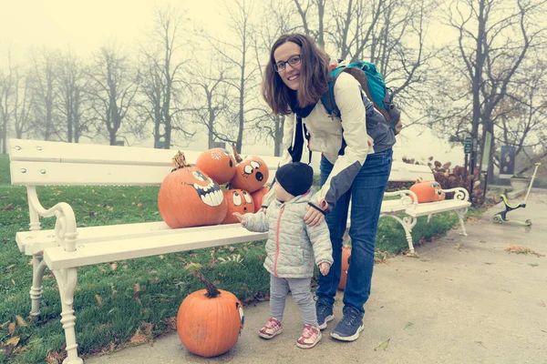 Mãe e filha explorando muitos pumpinks com rostos. — Fotografia de Stock