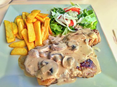 altın kızartması, salata ve champignon ve biber soslu bir biftek ile yemek 