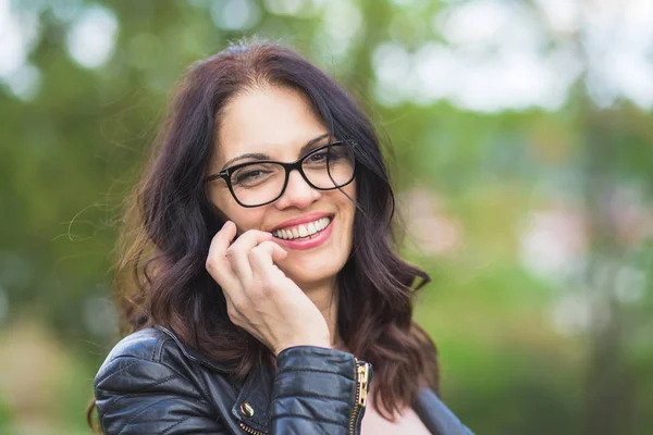 Bella donna di mezza età in giacca di pelle nera che parla al telefono . — Foto Stock