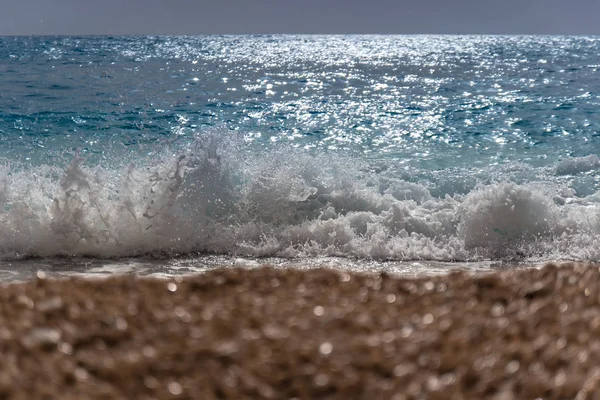 Close up de onda do mar respingo com espuma em uma praia de areia . — Fotografia de Stock