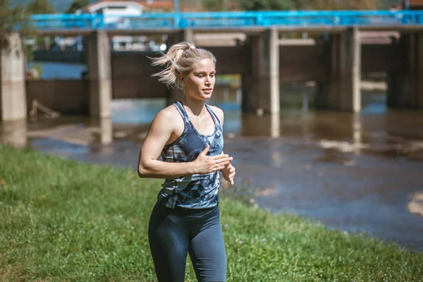 Фото молодой блондинки в спортивной одежде, бегущей по природе — стоковое фото