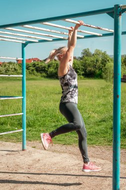 Sabahları parkta pratik yapan bir kız. Metal çubuklarla mukavemet uygulaması.