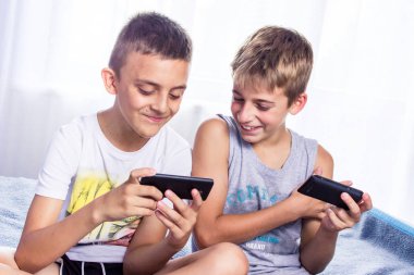 Sevimli küçük çocuklar, kardeşler akıllı telefonlarında online oyun oynuyor.