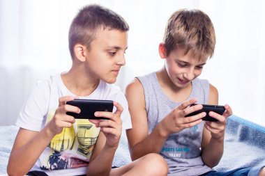 Sevimli küçük çocuklar, kardeşler akıllı telefonlarında online oyun oynuyor.
