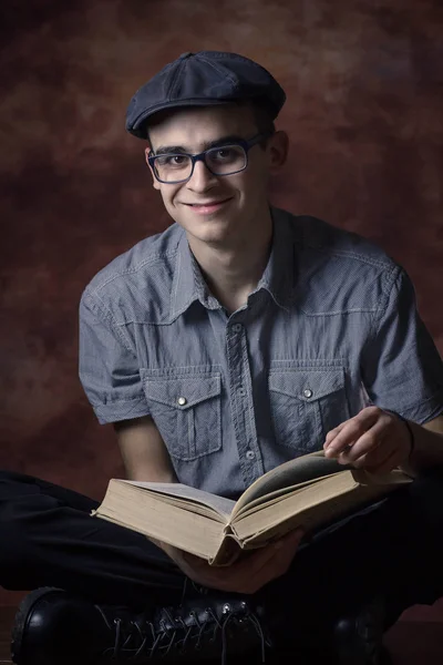 Jovem com chapéu de boina e óculos, lendo um livro . — Fotografia de Stock