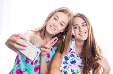 İki kız akıllı telefona bakıp selfie çekiyor. Sosyal medya kavramı