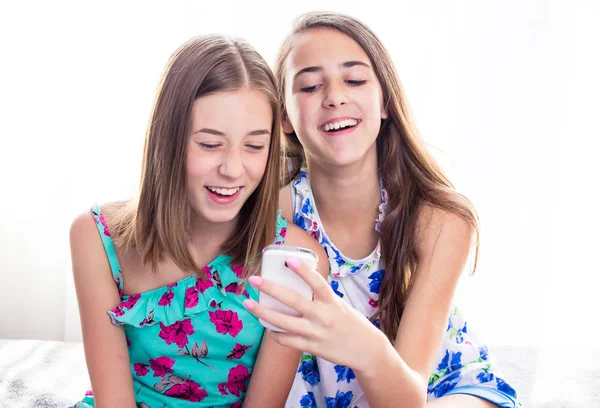 Two girls looking at smart phone, checking pictures on social media, smiling. — Stock Photo, Image