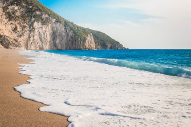 Kumlu bir plajda köpük ile deniz dalgası sıçrama. Yaz titreşimleri.