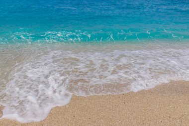 Kumlu bir plajda köpük ile deniz dalgası sıçrama yakın çekim. Lefkada, Yunanistan