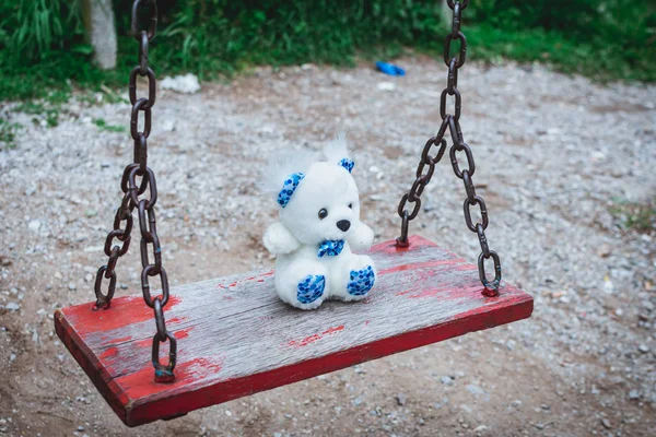 Oyuncak ayı parkta boş bir salıncakta yatıyor. Hüzün, kayıp çocuk günü