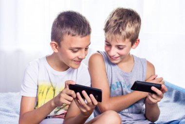 Sevimli, küçük çocuklar, kardeşler akıllı telefonlarında online oyun oynuyor.