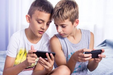 Sevimli, küçük çocuklar, kardeşler akıllı telefonlarında online oyun oynuyor.