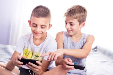 Sevimli, küçük çocuklar, kardeşler akıllı telefonlarında online oyun oynuyor.