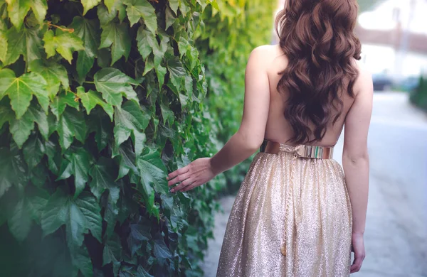 Adolescente en robe dorée glamour marchant près du mur vert , — Photo