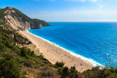 Turistlerle dolu mavi deniz ve kumlu plaj ile güzel yaz manzarası.