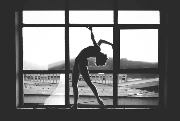 Черно-белое фото балерины в оконной раме в старом здании . — стоковое фото