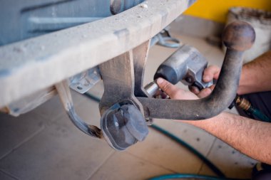 Araba tamircisi eski çekme kancasını arabadan çıkarıyor. Araba tamiri