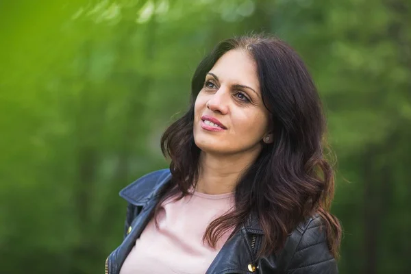 Mooie midden-leeftijd vrouw in zwart lederen jas glimlachend. — Stockfoto