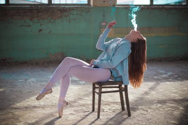 Ginger, sarışın balerin sandalyede sigara içiyor. Spor ve sigara konsepti