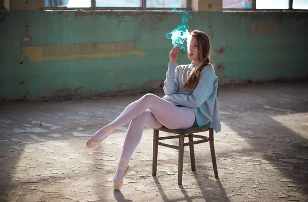 Ginger, blonde ballerina sitting on the chair smoking. Sport and smoking concept