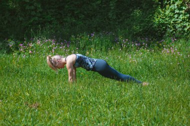 Sarışın kız doğada poz tahta yapıyor. Yoga konsepti