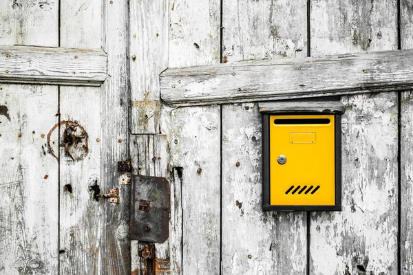 Puerta de madera vieja con buzón amarillo. Tablones verticales, fondo, texturas — Foto de Stock