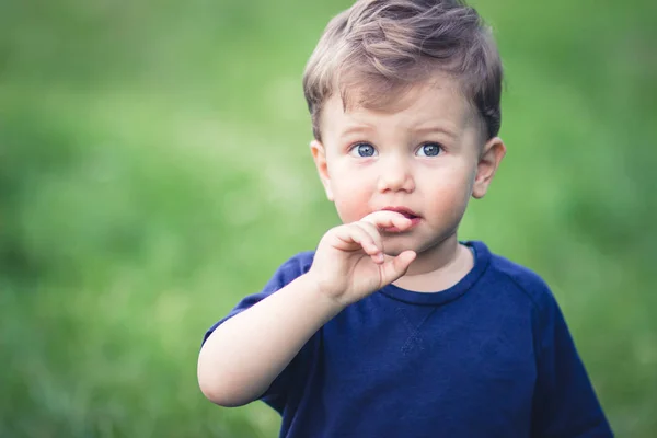 何かを見て美しい青い目を持つ青いTシャツのブロンドの少年 — ストック写真