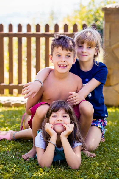 Retrato de duas meninas, irmãs e seu amigo menino se divertindo no quintal . — Fotografia de Stock