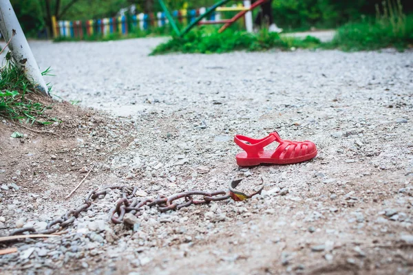 Детская сандалия лежит в песке с цепью. Международный день пропавших без вести — стоковое фото