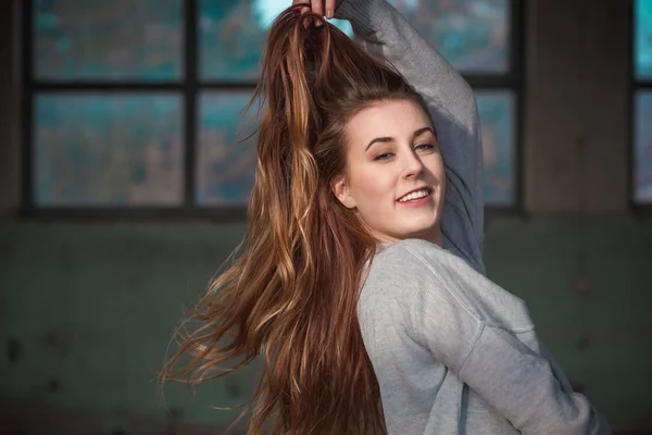 Schöne Teenager-Mädchen berührt ihre schönen langen roten Haare in grauem Pullover — Stockfoto