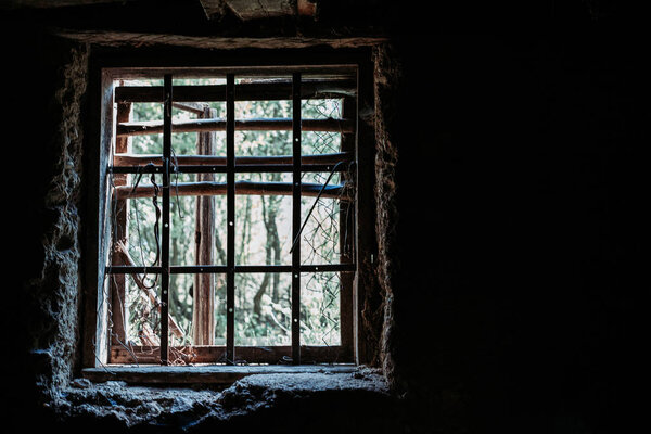 Old basement window with metal bars. Low light. Isolation, kidnapping concept