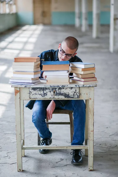 Foto de un estudiante con una pila de libros delante de él — Foto de Stock