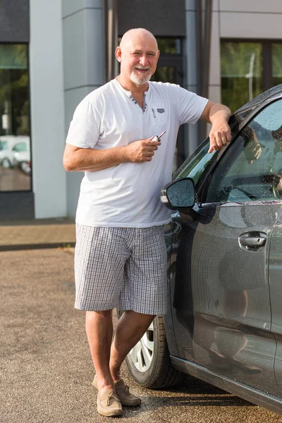 Middle aged man renting a car, holding keys. Transportation, transport concept