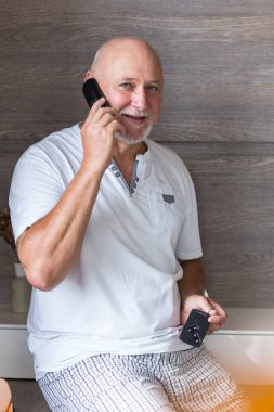 Orta yaşlı adam telefonda konuşuyor, arabanın anahtarlarını tutuyor..