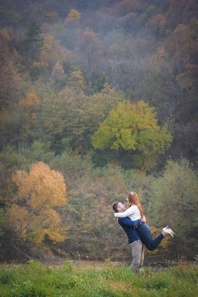 外で楽しいカップル、秋の雰囲気。空気中の女の子を持ち上げる少年. — ストック写真