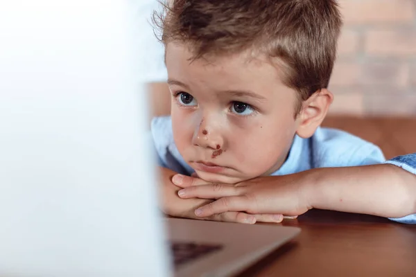 Ragazzo biondo carino attentamente guardando lo schermo del computer portatile. Bambini e tecnologia — Foto Stock
