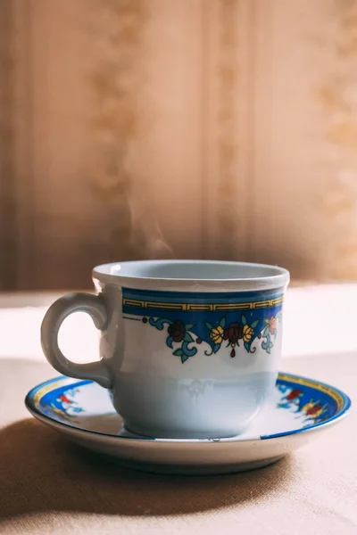 Cup of coffee on the table with steam. Retro, ceramic cup. Morning, breakfast